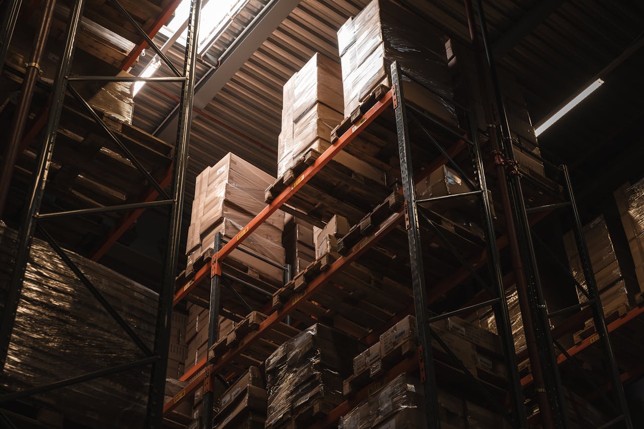 Interior view of a warehouse with stacked cardboard boxes on high shelves, showcasing storage and logistics.