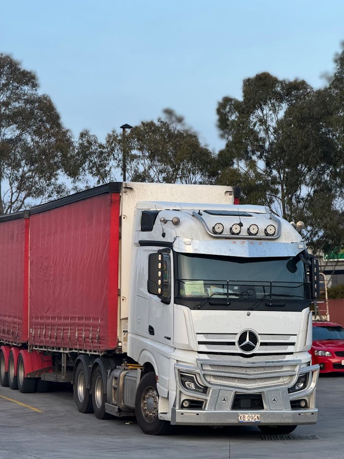 Services White and red semi truck parked outdoors at logistics hub, ready for transportation.